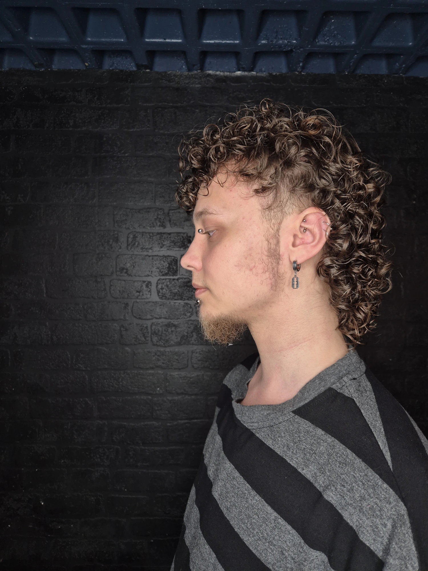 Men's curly textured haircut shown in profile