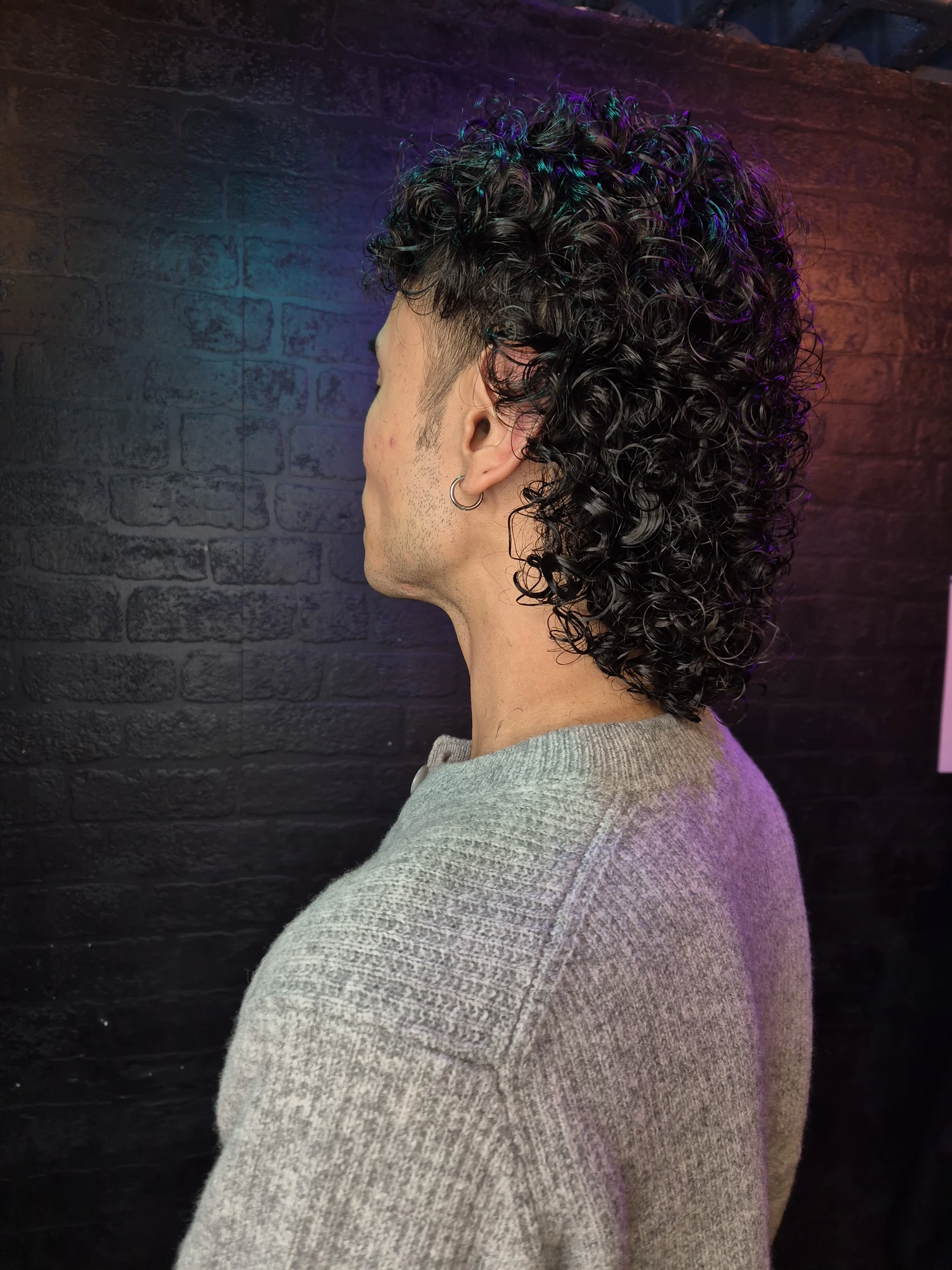 Men's textured curly hairstyle photographed from the side