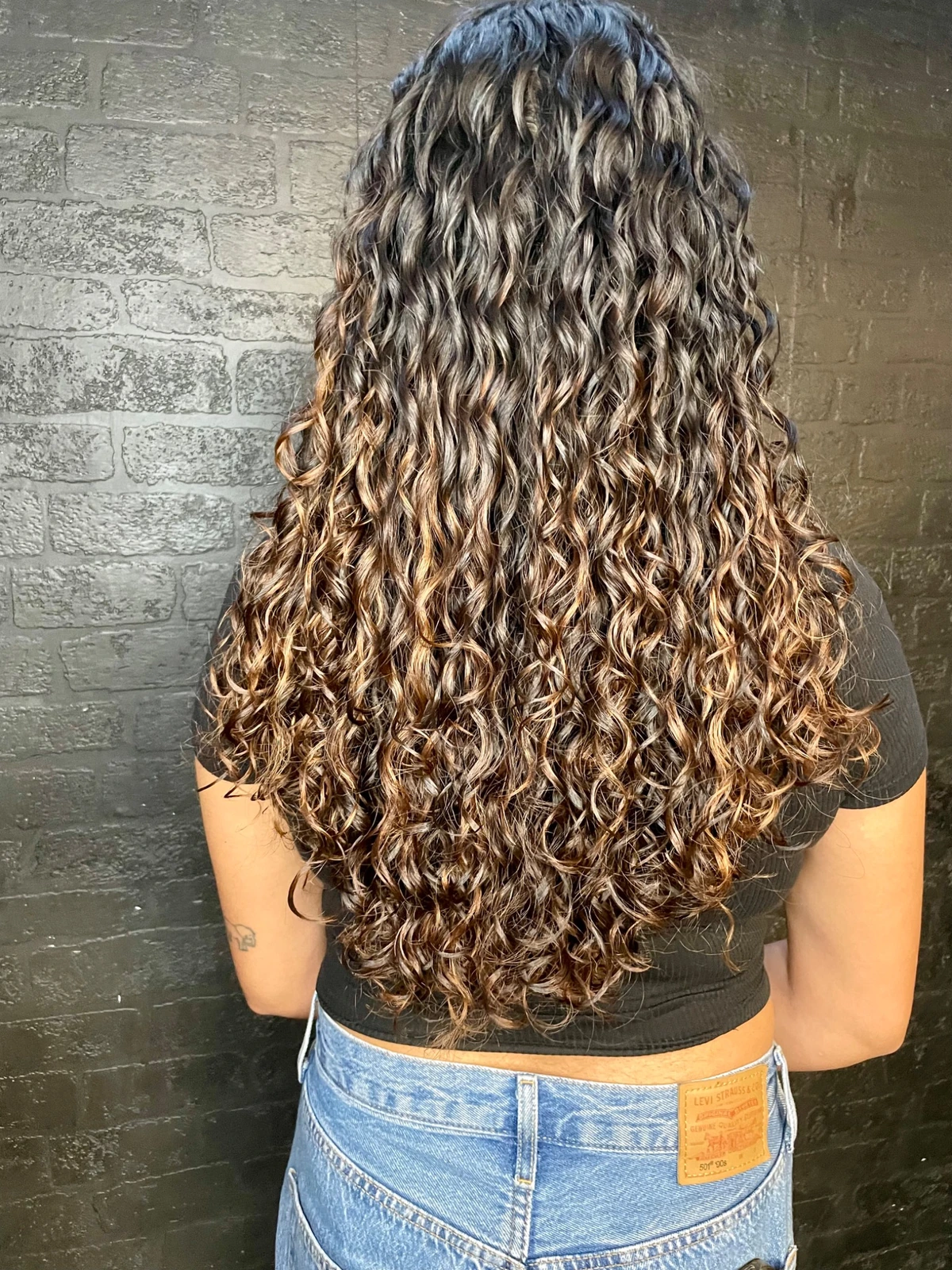 Long hair with soft, defined curls after an organic perm at Oliver Stephens