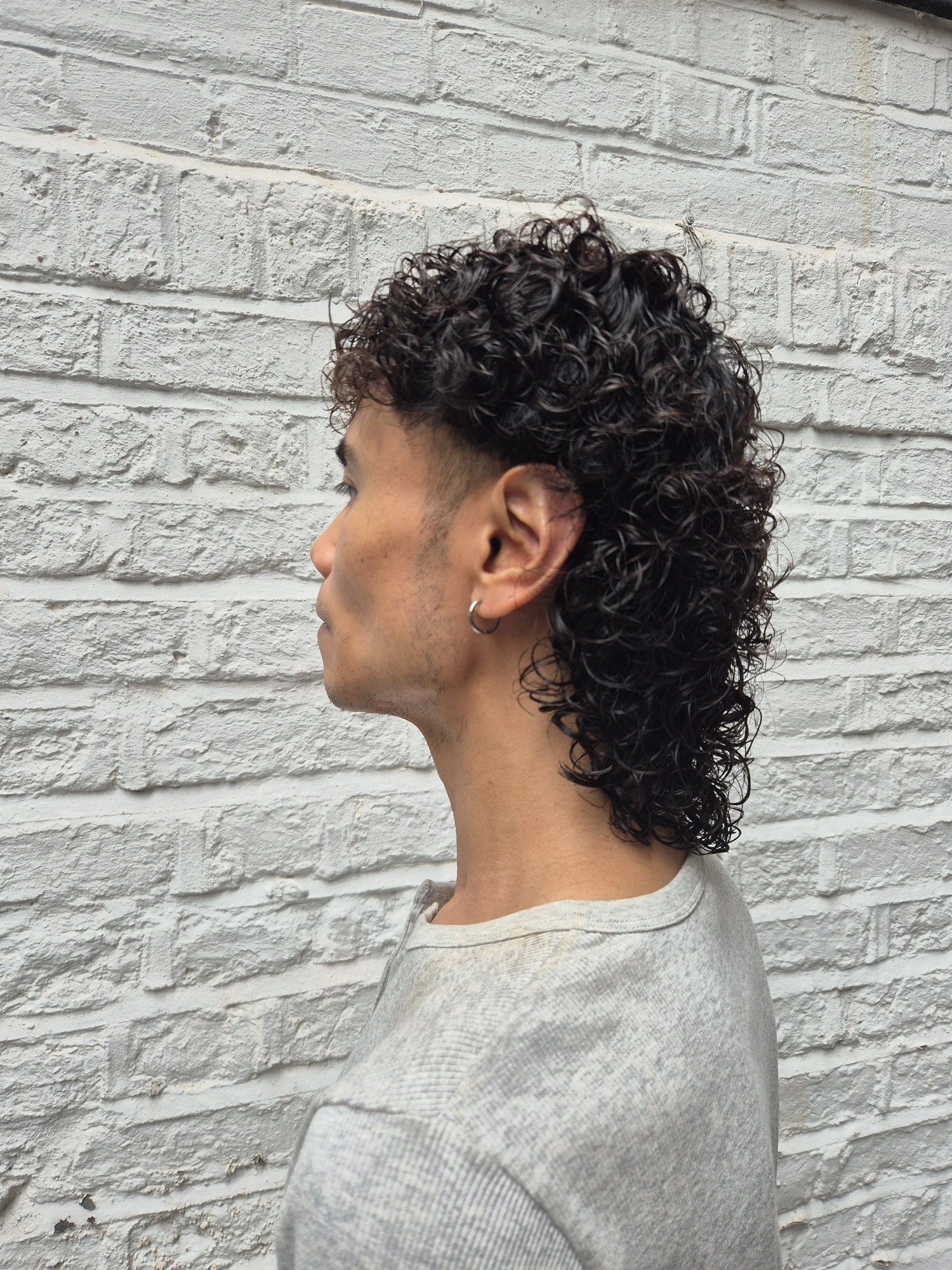 Men's short dark curly hairstyle photographed from the side